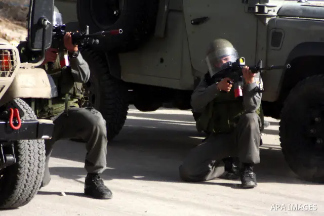 An Israeli soldier shoots tear gas towards Palestinians stone-throwers, not pictured, after clashes started during the funeral of Palestinian Youssef Ekhaleil in the West Bank village of Beit Omar, near Hebron, Saturday,...