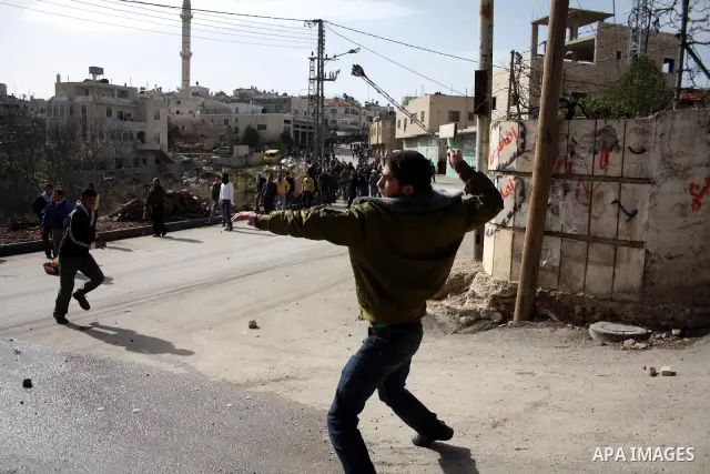Palestinians throw stones towards an Israeli army tower after clashes started during the funeral of Youssef Ekhaleil in the West Bank village of Beit Omar, near Hebron, Saturday, Jan. 29, 2011. Ekhaleil died of his wound...