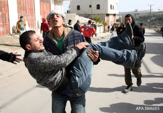 Palestinians carry a wounded youth after clashes with Israeli soldiers started during the funeral of Palestinian Youssef Ekhaleil in the West Bank village of Beit Omar, near Hebron, Saturday, Jan. 29, 2011. Ekhaleil died...