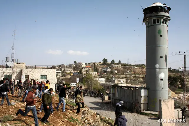 Palestinians throw stones towards an Israeli army tower after clashes started during the funeral of Youssef Ekhaleil in the West Bank village of Beit Omar, near Hebron, Saturday, Jan. 29, 2011. Ekhaleil died of his wound...
