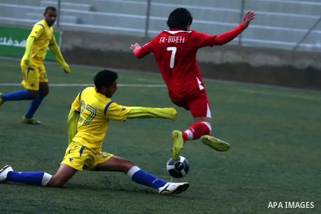 Palestinians play a football match between Tulkarem Center club (yellow) and Al-Beraeh Foundation club (red) in the occupied West Bank on Feb. 1,2011. Photo by Issam Rimawi
