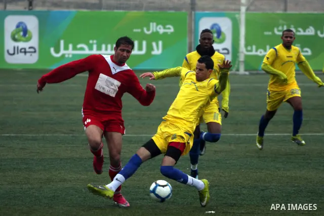 Palestinians play a football match between Tulkarem Center club (yellow) and Al-Beraeh Foundation club (red) in the occupied West Bank on Feb. 1,2011. Photo by Issam Rimawi