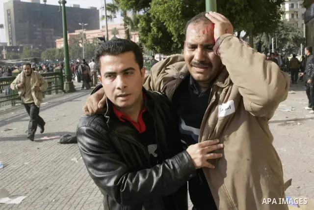 An Egyptian protester helps an injured man as pro Mubarak and anti Mubarak protesters clash in Tahrir square, in Cairo, Egypt, 02 February 2011. Media reports state on 02 February 2011 that clashes broke out in the main...