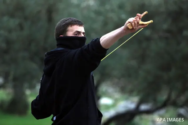A Palestinian youth hurls stones towards Israeli sildiers during a protest in the village of Bilin near Ramallah on Feb. 4, 2011. Photo by Issam Rimawi