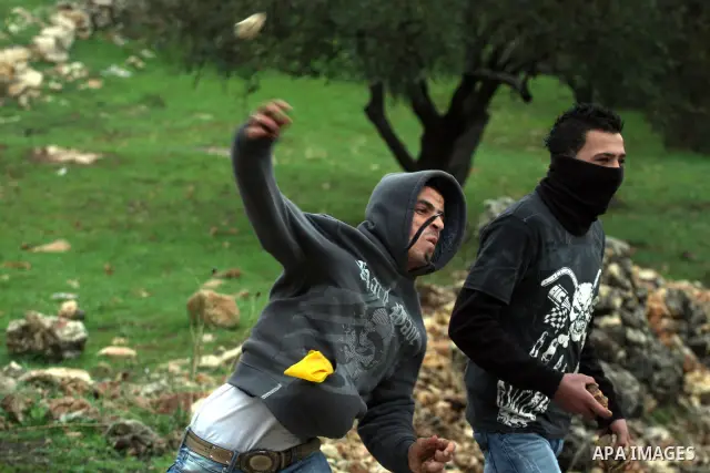 A Palestinian youth hurls stones towards Israeli sildiers during a protest in the village of Bilin near Ramallah on Feb. 4, 2011. Photo by Issam Rimawi