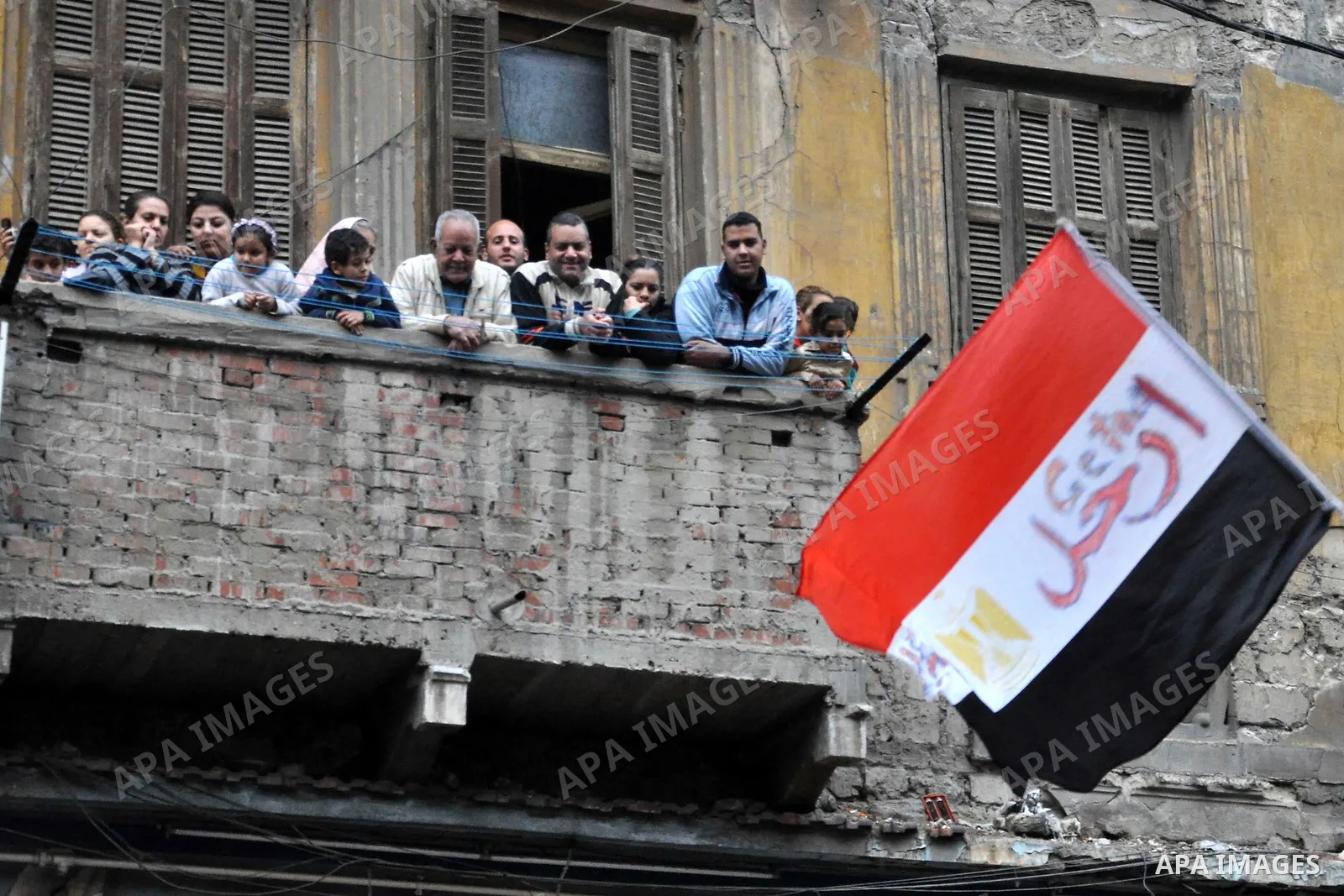 Egyptians look from their balcony at protesters during a protest called 'Sunday of the martyrs' in Alexandria, Egypt, 06 February 2011. Anti-government protests entered its 13th straight day in Egypt, as solutions were b...
