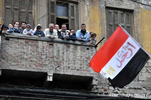 Egyptians look from their balcony at protesters during a protest called 'Sunday of the martyrs' in Alexandria, Egypt, 06 February 2011. Anti-government protests entered its 13th straight day in Egypt, as solutions were b...