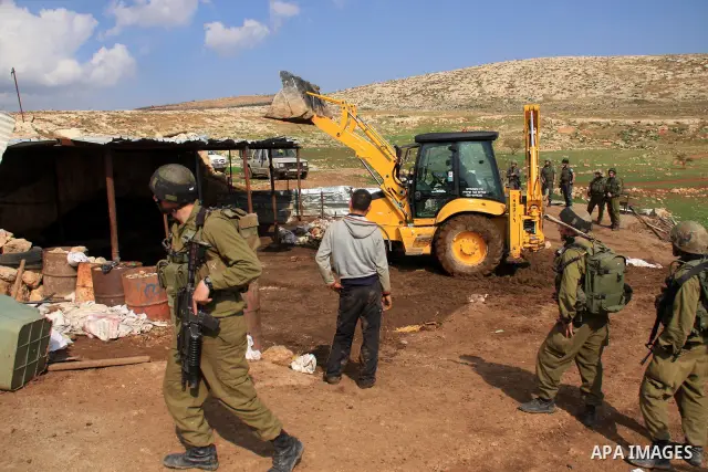 Israeli soldiers stand guards as a bulldozer of the Civil Administration during a demolition in the village of Khirbet Tana near the West Bank city of Nablus, Wednesday, Feb. 9, 2011. According to Palestinian witnesses a...