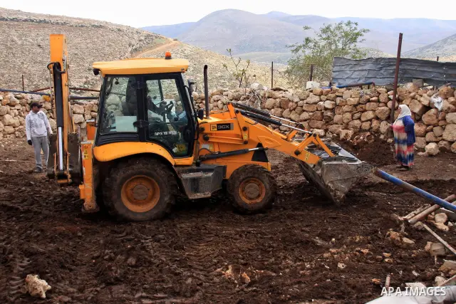 A Palestinian woman stands facing a bulldozer of the Civil Administration during a demolition in the village of Khirbet Tana near the West Bank city of Nablus, Wednesday, Feb. 9, 2011. According to Palestinian witnesses...