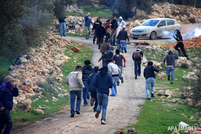 Palestinian youths run for cover from tear gas canisters fired by Israeli soldiers during the weekly demonstration against Israel's separation barrier in the West Bank village of Bilin near Ramallah, Friday, Feb. 11, 201...