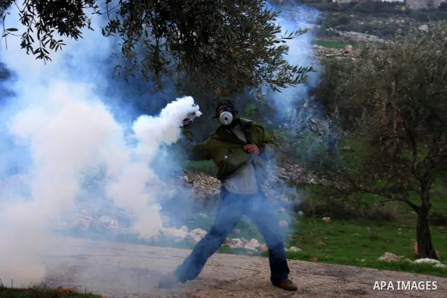 A Palestinian youth hurls tear gas canister back at Israeli soldiers during the weekly demonstration against Israel's separation barrier in the West Bank village of Bilin near Ramallah, Friday, Feb. 11, 2011. Photo by Wa...