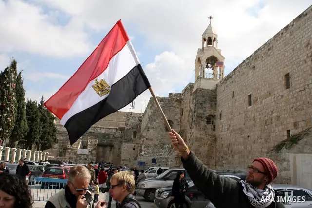 Palestinians hold Egypt and Palestine flags during a protest outside the Church of the Nativity in the West Bank town of Bethlehem 13 February 2011, to show support for the people of Egypt. Photo by Najeh Hashlamoun