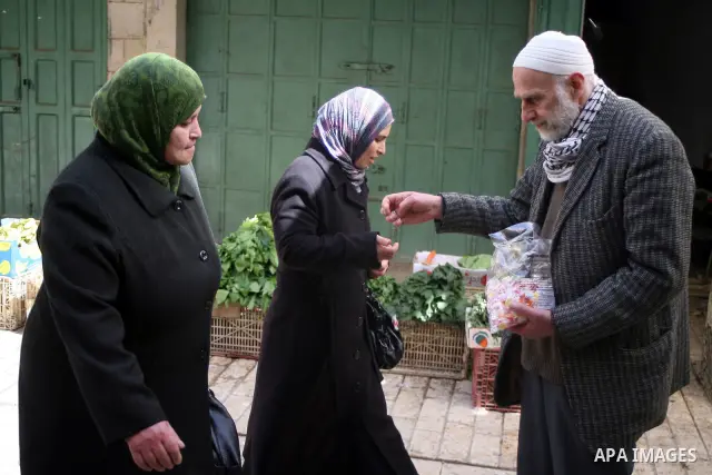 A Palestinian man distributes sweets as others go to Ibrahimi mosque as they march in a procession to mark the birth anniversary of Islam's prophet Mohammed, in the West Bank city of Hebron Tuesday, Feb. 15, 2011. Muslim...