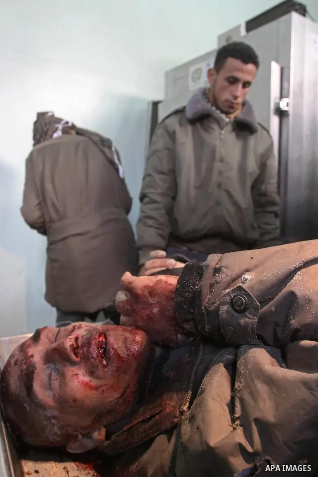 Palestinians stand next to the body of one of the three killed Palestinians, at the morgue in Kamal Adwan hospital in the town of Beit Lahiya, northern Gaza Strip, on Feb. 17, 2011. Three Palestinian fishermen were slain...