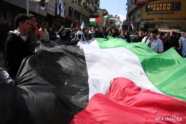 Palestinians hold a huge national flag during a rally calling for ending the Palestinian division, in the West Bank city of Ramallah on Feb. 17, 2011. More than 3000 protesters call for free elections and the reconciliat...