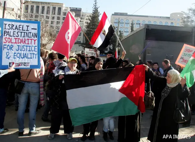 Palestinians, Israelis and foreign activists hold signs during a protest to show solidarity with Palestinian families against a Jewish settlement in the Sheikh Jarrah neighbourhood in East Jerusalem on Feb. 18, 2011. Pho...