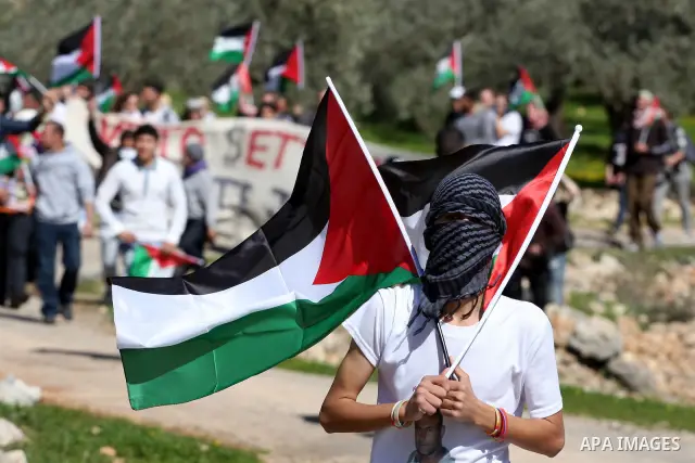 Palestinian protesters hold their national flag during the weekly demonstration against Israel's separation barrier in the West Bank village of Bilin near Ramallah, Friday, Feb. 18, 2011. Photo by Issam Rimawi