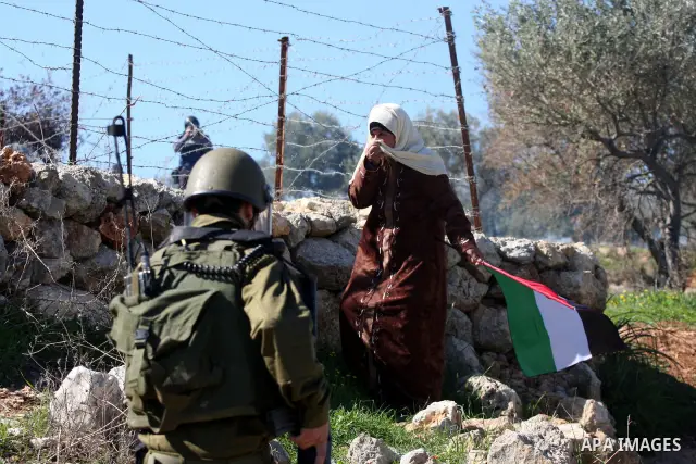 An Israeli soldier fires tear gas canisters towards protesters during the weekly demonstration against Israel's separation barrier in the West Bank village of Bilin near Ramallah, Friday, Feb. 18, 2011. Photo by Issam Ri...