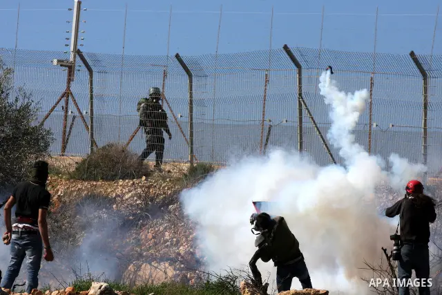 An Israeli soldier fires tear gas canisters towards protesters during the weekly demonstration against Israel's separation barrier in the West Bank village of Bilin near Ramallah, Friday, Feb. 18, 2011. Photo by Issam Ri...