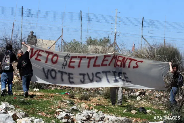 Protesters hold signs during the weekly demonstration against Israel's separation barrier in the West Bank village of Bilin near Ramallah, Friday, Feb. 18, 2011. Photo by Issam Rimawi
