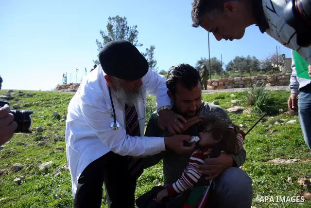Palestinian protesters help a wounded girl during the weekly demonstration against Israel's separation barrier in the West Bank village of Bilin near Ramallah, Friday, Feb. 18, 2011. Photo by Issam Rimawi