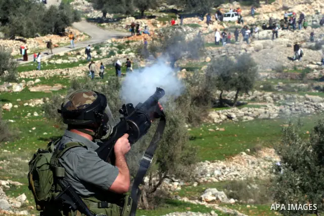 An Israeli soldier fires tear gas canisters towards protesters during the weekly demonstration against Israel's separation barrier in the West Bank village of Bilin near Ramallah, Friday, Feb. 18, 2011. Photo by Issam Ri...