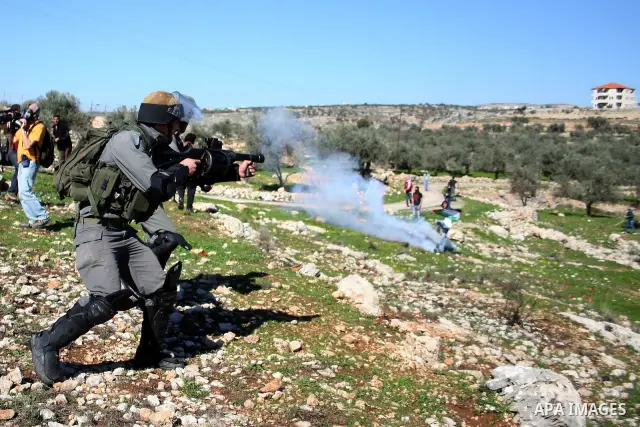 An Israeli soldier fires tear gas canisters towards protesters during the weekly demonstration against Israel's separation barrier in the West Bank village of Bilin near Ramallah, Friday, Feb. 18, 2011. Photo by Issam Ri...