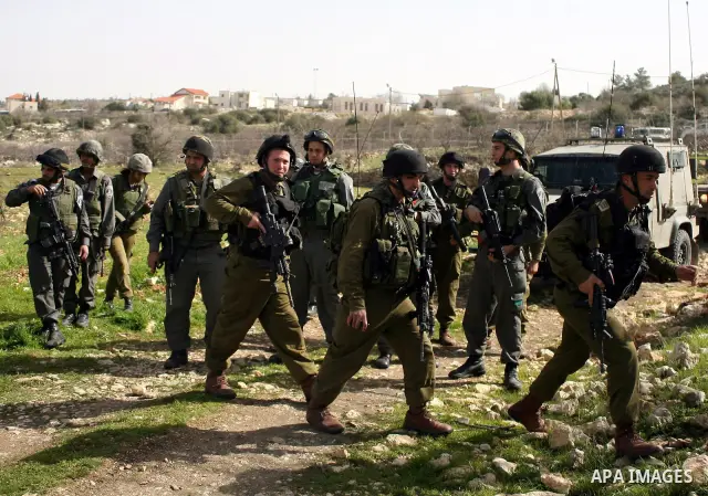 Israeli soldiers stand guard during a demonstration by Palestinian, Israeli and foreign activists against the demolishing of farm land to be used in the construction of Jewish settlements near the existing Israeli settle...