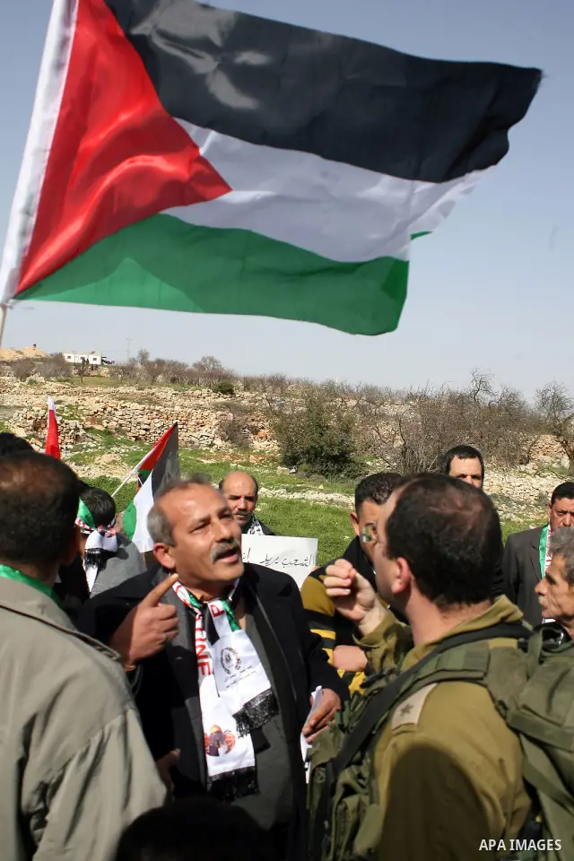 An Israeli soldier argues with a protester during a demonstration by Palestinian, Israeli and foreign activists against the demolishing of farm land to be used in the construction of Jewish settlements near the existing...