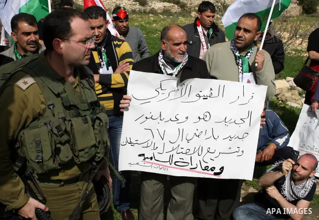 Israeli soldiers stand guard during a demonstration by Palestinian, Israeli and foreign activists against the demolishing of farm land to be used in the construction of Jewish settlements near the existing Israeli settle...