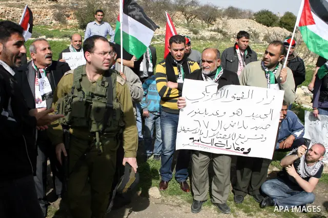 Israeli soldiers stand guard during a demonstration by Palestinian, Israeli and foreign activists against the demolishing of farm land to be used in the construction of Jewish settlements near the existing Israeli settle...