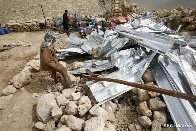 Palestinians sits next to her belongings following the demolition of her home aftar Israeli army bulldozer destroys a Palestinian home, in the village of Khirbet Tana near the West Bank city of Nablus, in the so-called A...