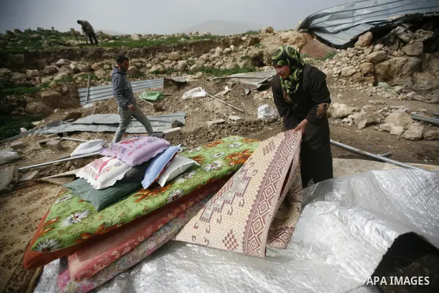 Palestinians sits next to her belongings following the demolition of her home aftar Israeli army bulldozer destroys a Palestinian home, in the village of Khirbet Tana near the West Bank city of Nablus, in the so-called A...