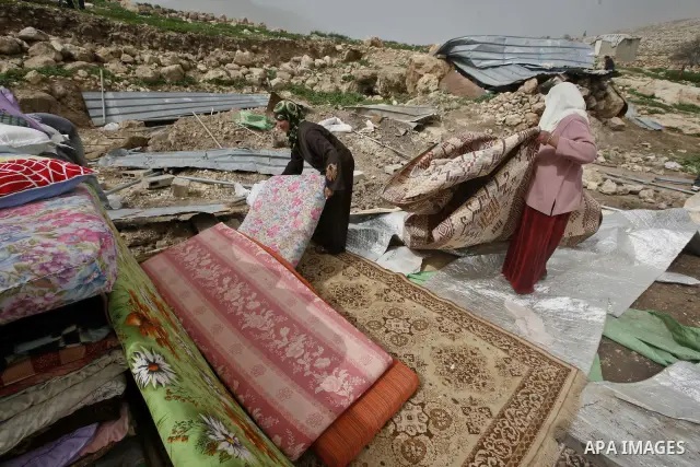 Palestinians sits next to her belongings following the demolition of her home aftar Israeli army bulldozer destroys a Palestinian home, in the village of Khirbet Tana near the West Bank city of Nablus, in the so-called A...