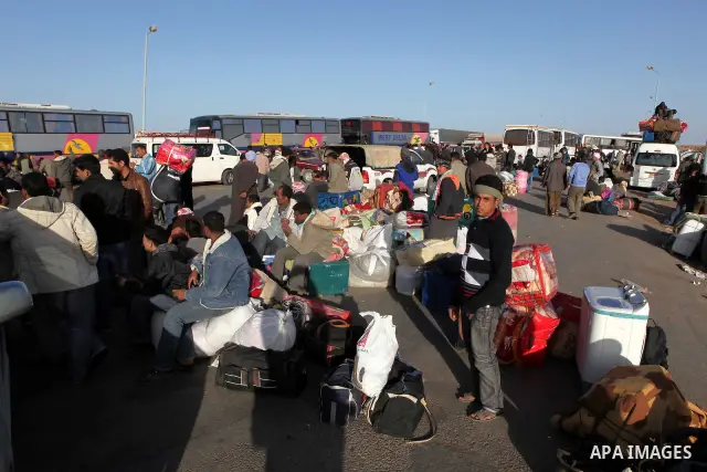 Egyptians, who have fled from Libya through the Salloum land port gate wait with their luggage,Tuesday, Feb. 22, 2011. An estimated 5,000 Egyptians have returned home from Libya by land, and about 10,000 more are waiting...