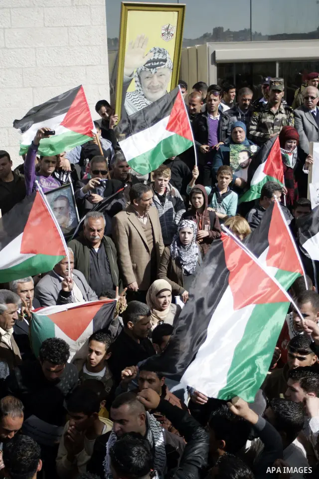Palestinian protesters hold national flags and banners during a rally against the U.S. veto and calling for the national reconciliation in the West Bank city of Bethlehem, on Feb. 23, 2011. Photo by Najeh Hashlamoun