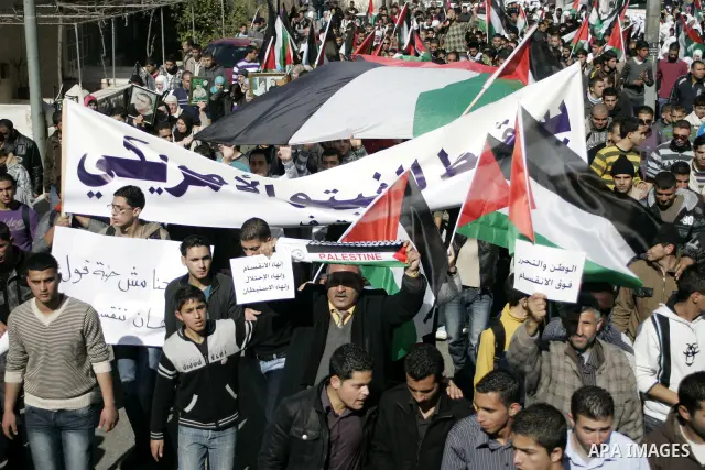 Palestinian protesters hold national flags and banners during a rally against the U.S. veto and calling for the national reconciliation in the West Bank city of Bethlehem, on Feb. 23, 2011. Photo by Najeh Hashlamoun