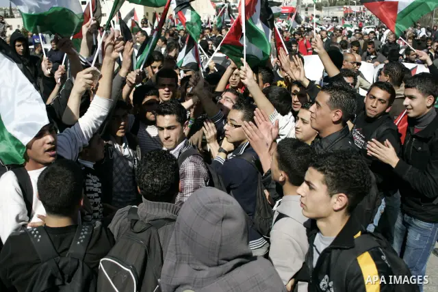 Palestinian protesters hold national flags and banners during a rally against the U.S. veto and calling for the national reconciliation in the West Bank city of Bethlehem, on Feb. 23, 2011. Photo by Najeh Hashlamoun