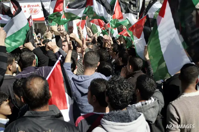 Palestinian protesters hold national flags and banners during a rally against the U.S. veto and calling for the national reconciliation in the West Bank city of Bethlehem, on Feb. 23, 2011. Photo by Najeh Hashlamoun