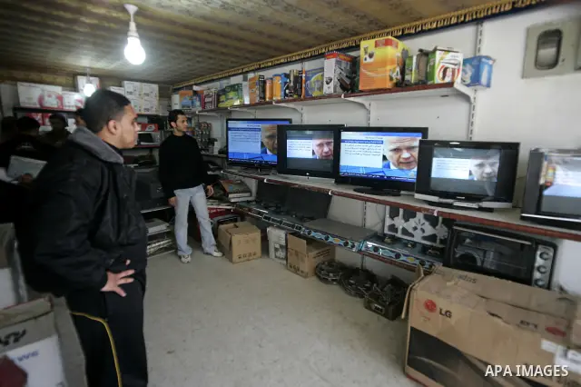 Palestinian men look on the television to watch the hot events in Libya, in Rafah, southern Gaza Strip on February 24, 2011. Palestinian sources confirmed Thursday morning that the Libyan leader Muammar Gaddafi has threa...