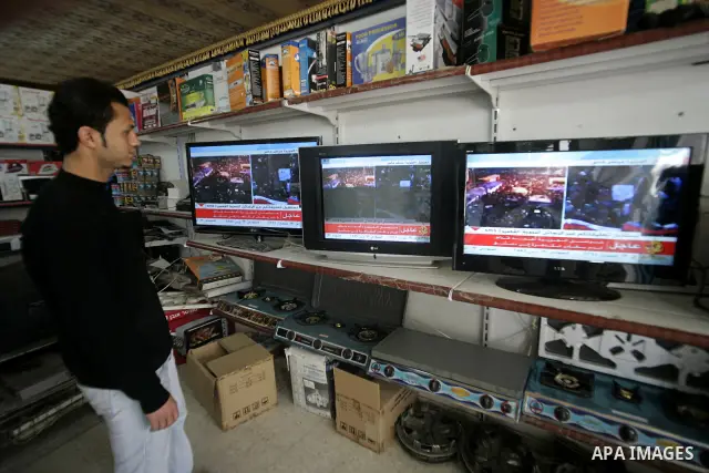A Palestinian man looks on the television to watch the hot events in Libya, in Rafah, southern Gaza Strip on February 24, 2011. Palestinian sources confirmed Thursday morning that the Libyan leader Muammar Gaddafi has th...