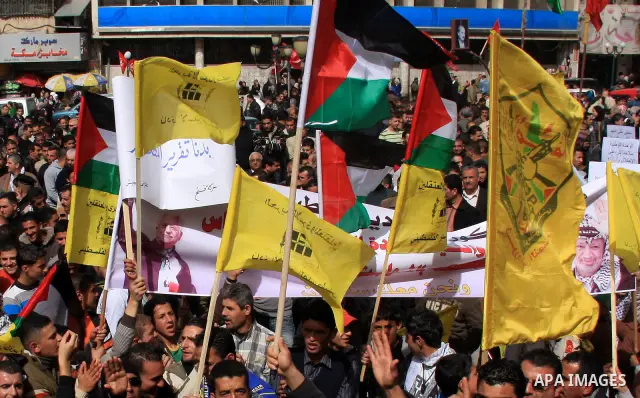 Palestinian protesters hold national and Fatah movement flags and banners during a rally against the U.S. veto and calling for the national reconciliation in the West Bank city of Nablus, Thursday, Feb. 24, 2011. Photo b...