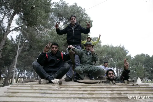 Anti-government protesters make victory signs as they stand on an army tank near a square where people are protesting in ALbedi city, Libya, February 24, 2011. Thousands of Libyans celebrated the liberation of the easter...