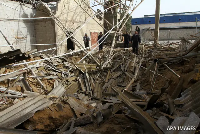 Palestinians walk across a damaged warehouse following an Israeli air strike in Nuseirat refugee camp, central Gaza Strip, Thursday, Feb. 24 , 2011. Overnight, Israeli aircraft carried out air strikes against targets in...