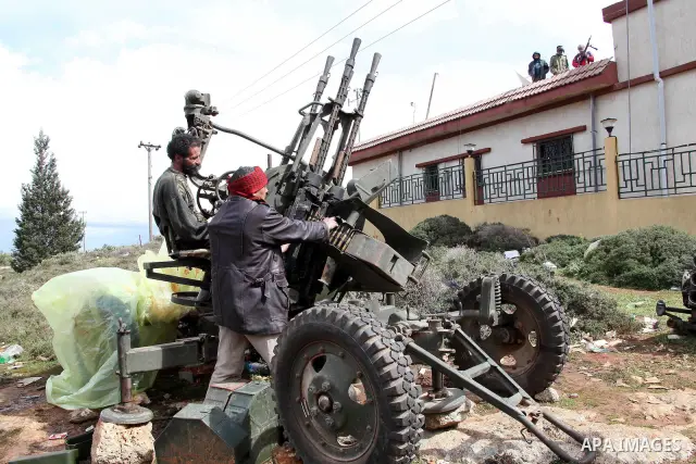 A Libyan gunman as he holds his automatic machine gun , in Albedia , Libya, on Thursday Feb. 24, 2011. A Libyan witness says a Libyan army unit has blasted a minaret of a mosque in a city west of Tripoli. The witness tel...