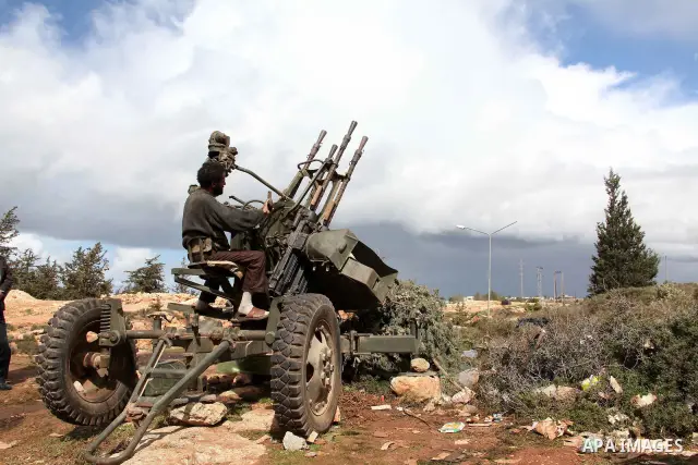 A Libyan gunman as he holds his automatic machine gun , in Albedia , Libya, on Thursday Feb. 24, 2011. A Libyan witness says a Libyan army unit has blasted a minaret of a mosque in a city west of Tripoli. The witness tel...