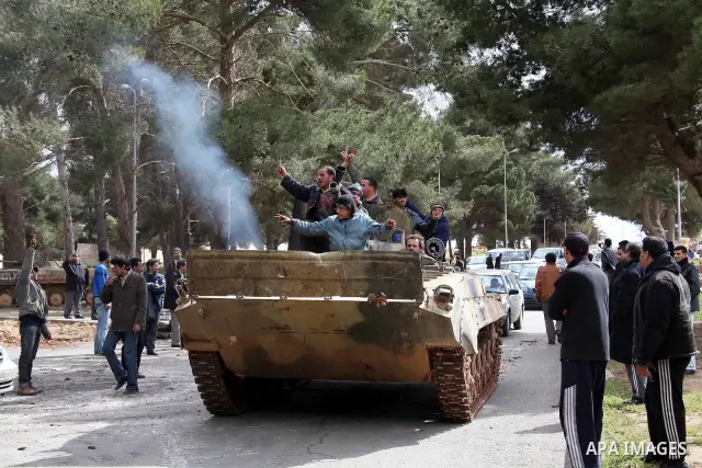 Anti-government protesters make victory signs as they stand on an army tank near a square where people are protesting in ALbedi city, Libya, February 24, 2011. Thousands of Libyans celebrated the liberation of the easter...
