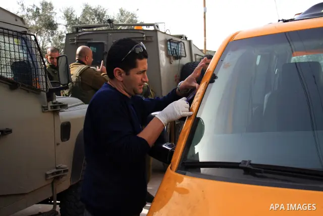 An Israeli soldier guards as a damaged car in the village of Jeet the West bank city of Qalqilya, Friday,25, 2011. Palestinians and the Israeli military said Friday Jewish settlers vandalized in a Palestinian village in...