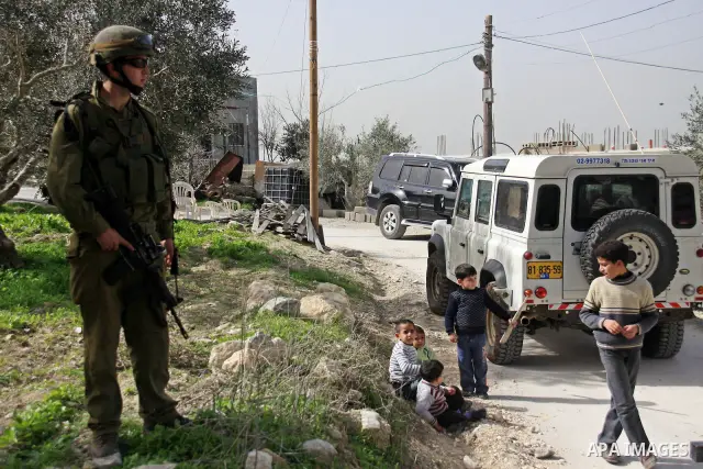 An Israeli soldier next to boys in the village of Jeet the West bank city of Qalqilya, Friday,25, 2011. Palestinians and the Israeli military said Friday Jewish settlers vandalized in a Palestinian village in the West Ba...