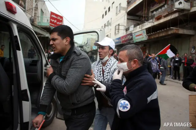 Palestinian medics help wounded Palestinian youths during a protest against the continued closure of Shuhada street to Palestinians, in the West Bank city of Hebron 25 February 2011. The activists gathered on Friday call...